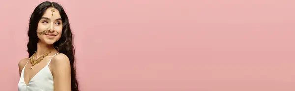 A stunning indian woman in a flowing white dress strikes a pose against a vibrant pink backdrop. — Stock Photo
