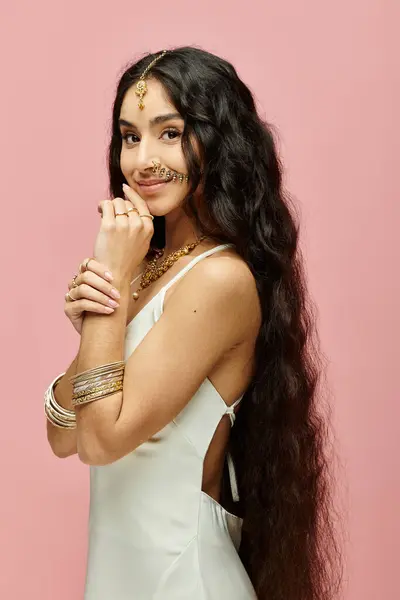 A beautiful indian woman with long hair striking a pose on a vibrant pink background. — Stock Photo
