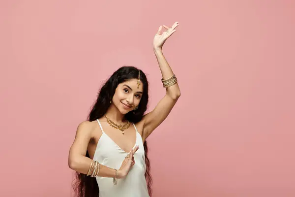 Graceful indian woman in white dress dancing on vibrant pink backdrop. — Stock Photo