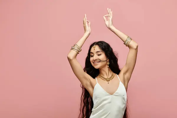 Indian woman in white dress dances on pink background. — Stock Photo