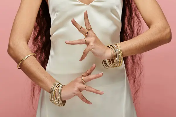 A classy indian woman in a white dress adorned with gold rings strikes a captivating pose. — Stock Photo