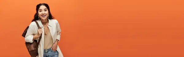 Smiling indian woman against vibrant orange backdrop. — Stock Photo