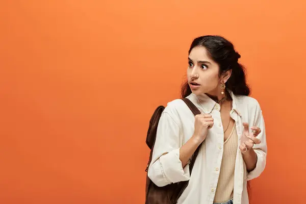 Jeune femme indienne avec sac à dos contre le mur orange — Photo de stock