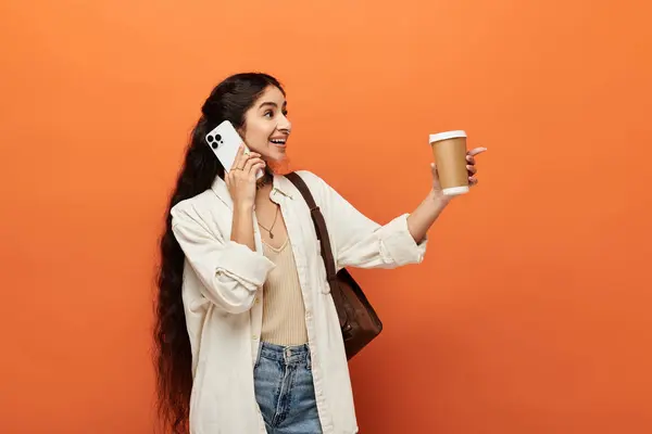 Femme indienne élégante tenant une tasse de café, parlant au téléphone. — Photo de stock
