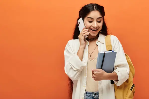 Young indian woman in urban setting talks on phone, holding backpack. — Stock Photo