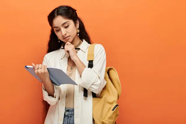 Mujer india con una mochila examina el portapapeles con atención. - foto de stock