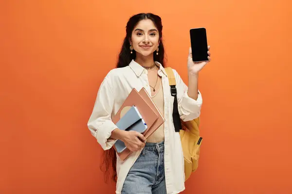 Young indian woman holding phone and backpack in urban setting. — Stock Photo