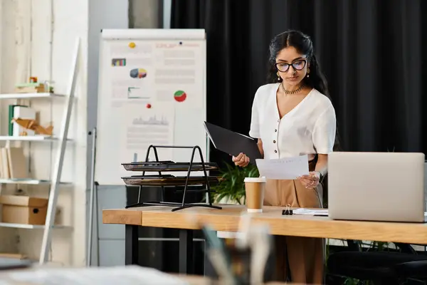 A stylish young indian woman stands confidently in an office setting. — Stock Photo