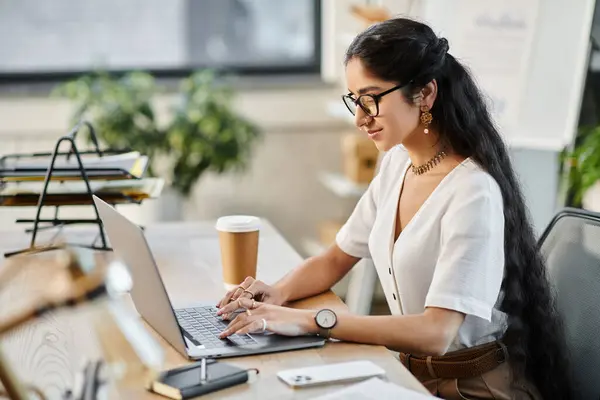 Uma jovem indiana trabalha energicamente em um laptop em um ambiente de escritório moderno. — Fotografia de Stock