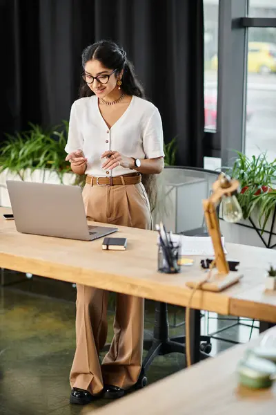 Young indian woman energetically working on a laptop at a stylish desk. — Stock Photo