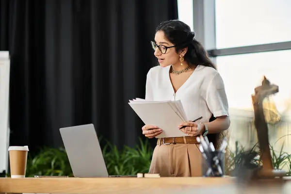 Young indian woman in glasses works diligently at desk with laptop. — Stock Photo