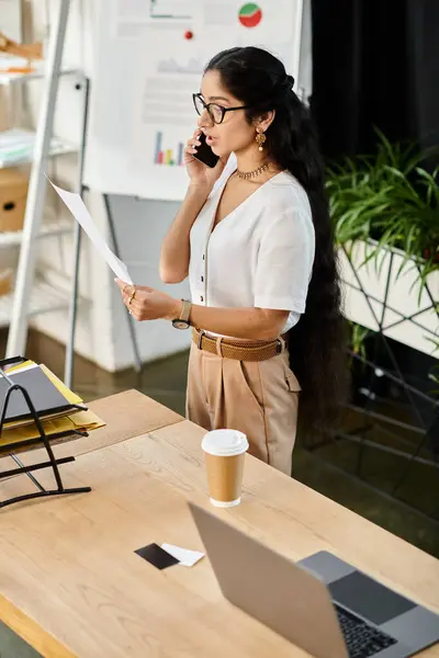 Young indian woman, stylishly dressed, talking on phone, standing at desk. — Stock Photo