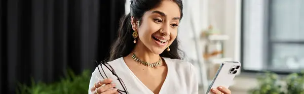A indian woman smiling while holding a phone. — Stock Photo
