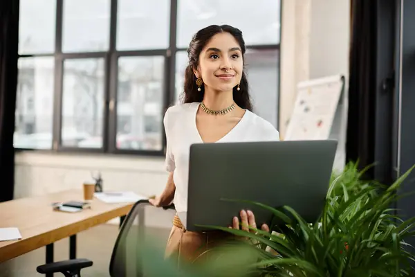 Young indian woman standing in office, using laptop. — Stock Photo