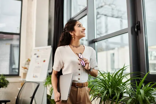 Charismatic indian woman standing by office window, radiating confidence. — Stock Photo