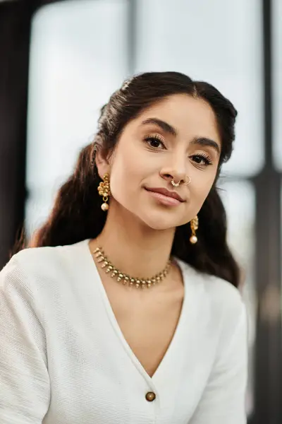 A young indian woman exudes elegance in a white shirt and gold jewelry. — Stock Photo