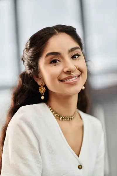 Une jeune femme indienne respire l'élégance dans une chemise blanche associée à des bijoux en or. — Photo de stock