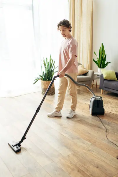Чоловік у затишному домашньому вбранні використовує вакуум для чищення підлоги. — стокове фото
