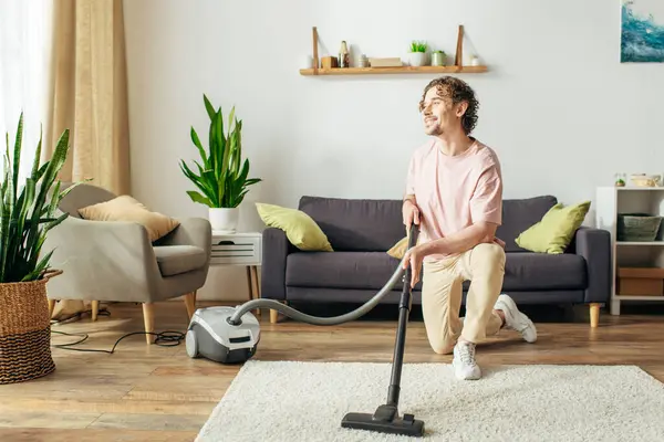 A man in cozy homewear diligently vacuums a living room. — Stock Photo