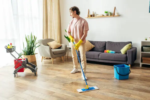 Un uomo in accogliente casalinghi energicamente pulire il pavimento del soggiorno. — Foto stock