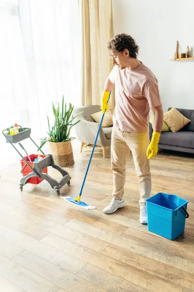 Handsome man in cozy homewear mopping and cleaning a living room. — Stock Photo