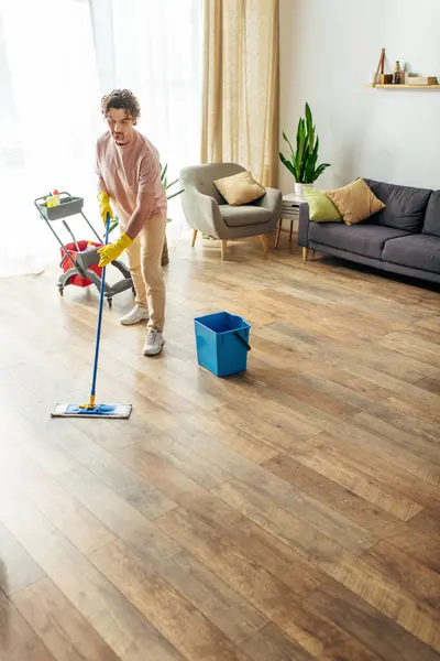 Man elegantly mopping living room floor. — Stock Photo