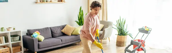 A man in a bright room cleans the floor with a mop. — Stock Photo