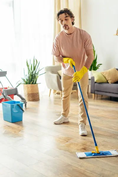 Bello uomo in accogliente biancheria da casa pulire il pavimento. — Foto stock