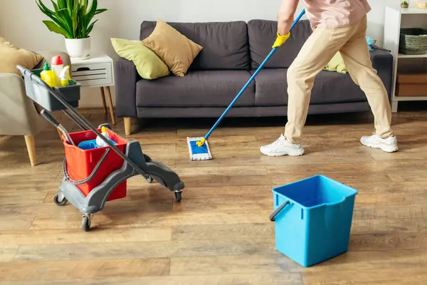 Чоловік в дії, прибирає підлогу мопедом у затишній домашній обстановці. — стокове фото