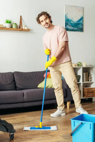 Um homem bonito em roupa de casa acolhedora esfrega o chão. — Fotografia de Stock