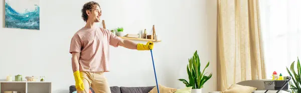 A man in cozy homewear mopping the living room floor. — Stock Photo
