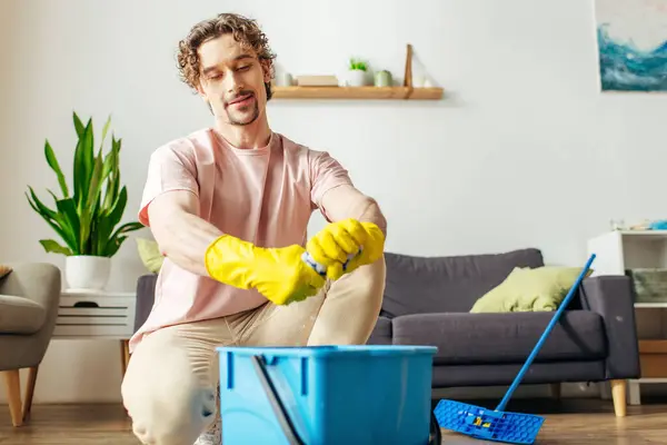 A handsome man in cozy homewear cleans the floor with a mop. — Stock Photo