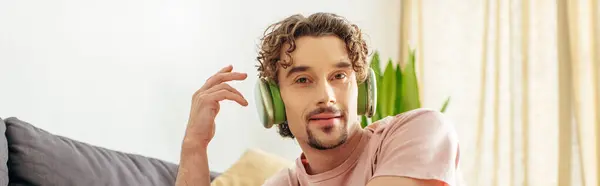 Handsome man sitting on a couch with headphones. — Stock Photo