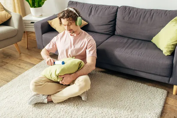 Handsome man in cozy attire tenderly cleaning pillow with sticky roller. — Stock Photo