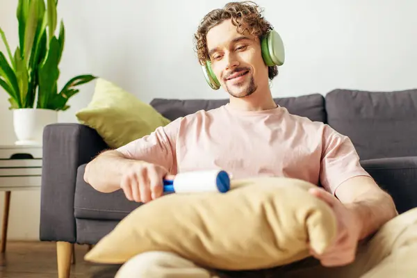 Handsome man in cozy homewear enjoying music near couch with headphones. — Stock Photo