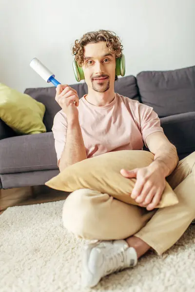 Ein Mann in bequemer Hauskleidung sitzt auf dem Boden, Kopfhörer tragend, eingetaucht in Musik. — Stockfoto