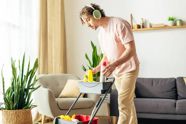 Um homem em roupa de casa aconchegante está energeticamente limpando sua sala de estar. — Fotografia de Stock