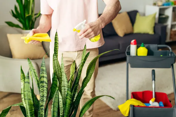 A handsome man in cozy homewear cleaning his house with care. — Stock Photo
