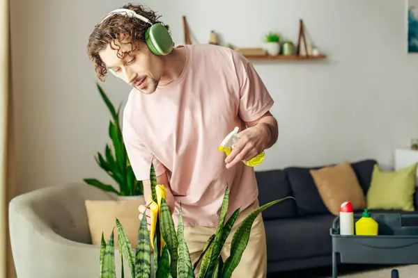 Stylish man in a pink shirt listens to music near a green plant. — Stock Photo