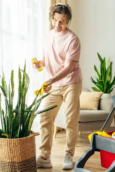 A man in cozy homewear cleaning plants. — Stock Photo