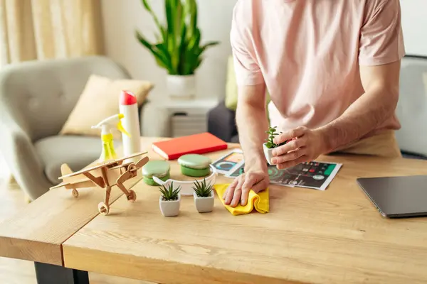 A man in cozy homewear sitting at a table cleaning near laptop. — Stock Photo