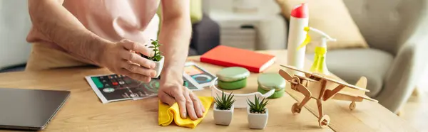A handsome man in cozy homewear cleaning a table with a cloth. — Stock Photo
