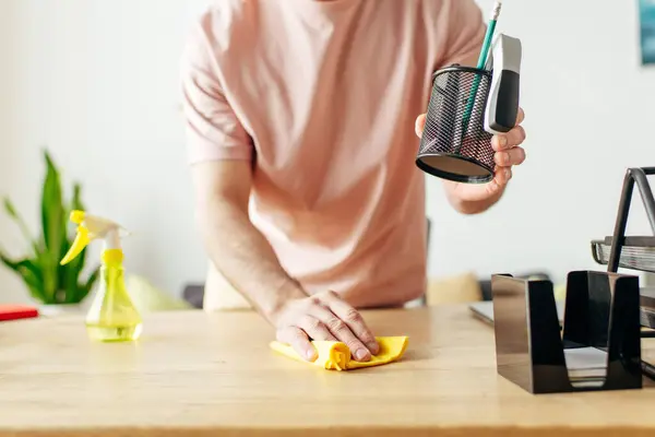 A suave man in cozy attire cleans a table with a sponge. — Stock Photo