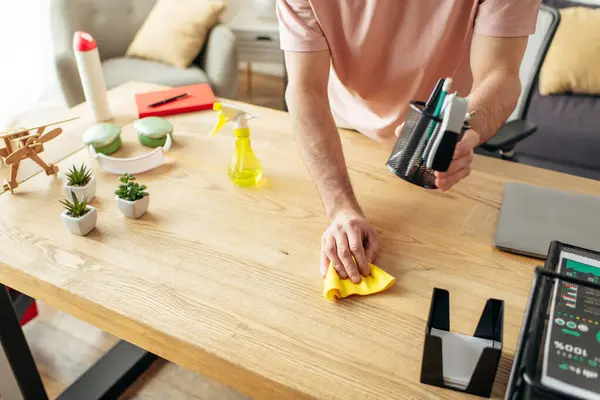 Handsome man in cozy homewear diligently cleaning a table with a sponge. — Stock Photo