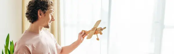 Мужчина в уютной одежде держит в руке игрушечный самолет.. — стоковое фото