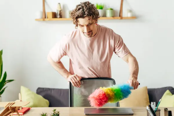 A man in cozy homewear holding a colorful duster. — Stock Photo