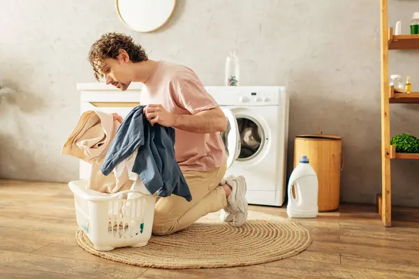 Un hombre en ropa de casa acogedora sentado al lado de una lavadora. - foto de stock