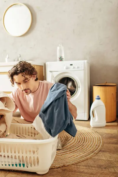 Um homem bonito em roupa de casa aconchegante lavando roupa em uma cesta de lavanderia. — Fotografia de Stock
