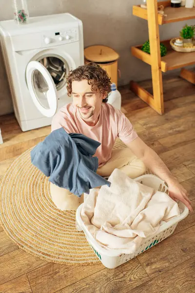 Man in homewear sitting beside pile of clothes. — Stock Photo