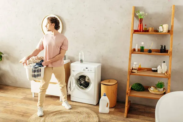 Man stands by washer, holding laundry basket. — Stock Photo